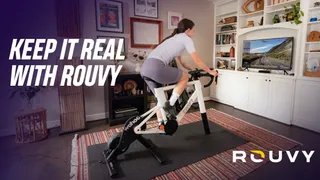 A rider on an indoor bike connected up to ROUVY next to text that reads "Keep it real with ROUVY"