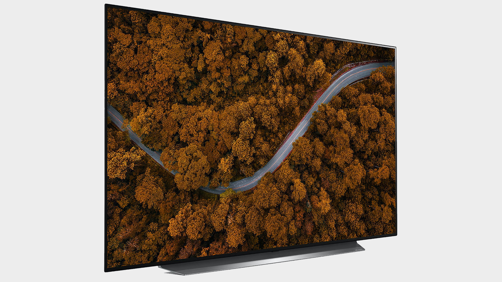LG OLED48CX 4K TV on a grey background with a top down shot of a road through a forest on the screen