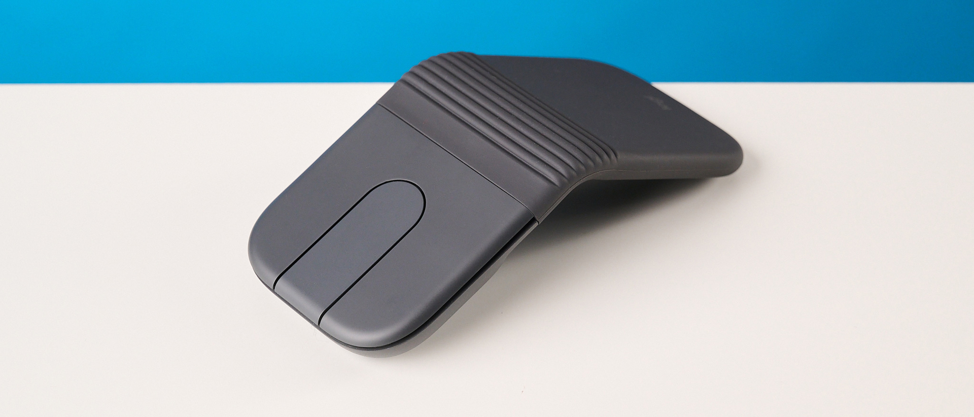 Logitech Mobi Fold mouse in graphite photographed in front of a blue background