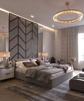 large bedroom with chevron effect wall panelled section behind bed, large modern circular pendant light, bedside tables and brown and white rug