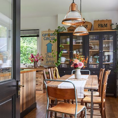 vintage style kitchen diner with mismatched chairs. industrial style pendant lights, kitchen dresser and wooden handmade cabinets