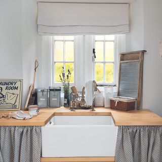 Farmhouse kitchen with grey cupboard curtains, a belfast sink and wooden worktops.