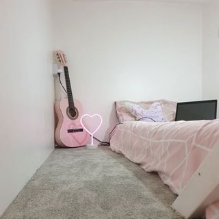 Bedroom with grey carpet and pink guitar