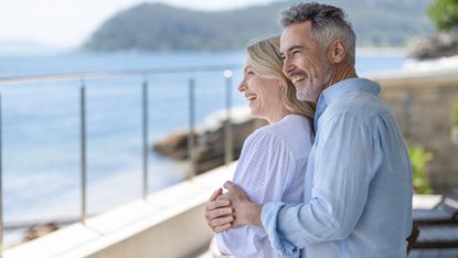 A mature couple stand on a balcony.