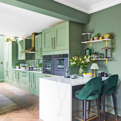 a green kitchen with a breakfast bar and velvet upholstered bar stools