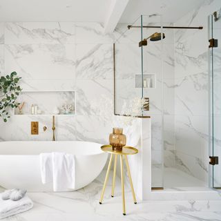bathroom with white bath marble tiled walls and brass hardware