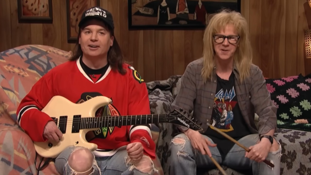 From left to right Mike Myers as Wayne holding a guitar and Dana Carvey as Garth holding drum stikcs in the SNL 40 Wayne's World sketch. 