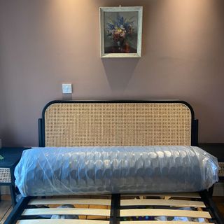 The Origin Hybrid mattress being tested in a bedroom with pink walls and a bed with a rattan headboard