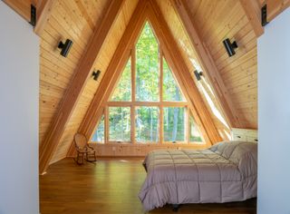 bedroom at the top of the triangle shaped ceiling at Lake Placid A-Frame by Strand Design