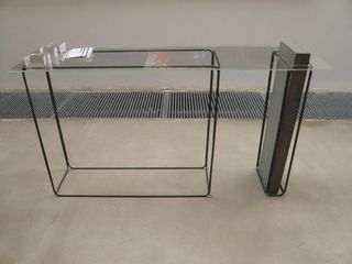 Table made from glass, metal rods and a block of concrete