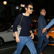 Harry Styles steps out wearing straight-leg jeans with a navy jumper, loafers and a leopard print Chanel bag.