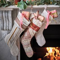 three christmas stockings filled with Wellness Christmas gifts hanging on a mantelpiece beside a fire