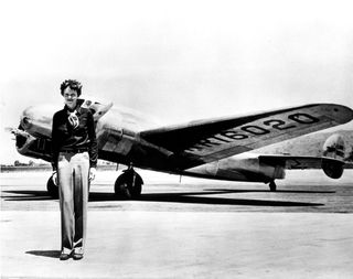 Amelia Earhart stands in front of her Lockheed Electra.