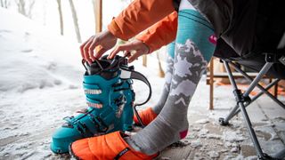 Person wearing ski socks putting on ski boots