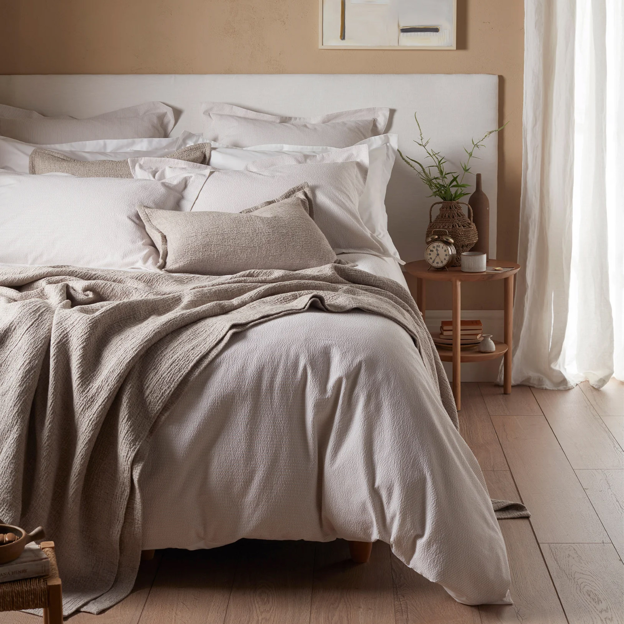 A bed dressed in Secret Linen Store bedding in natural tones