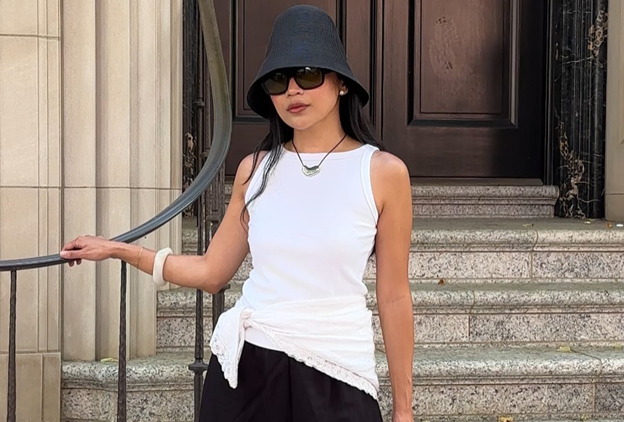 Woman wearing white tank, black shorts, sunglasses in black bucket hat outfit.
