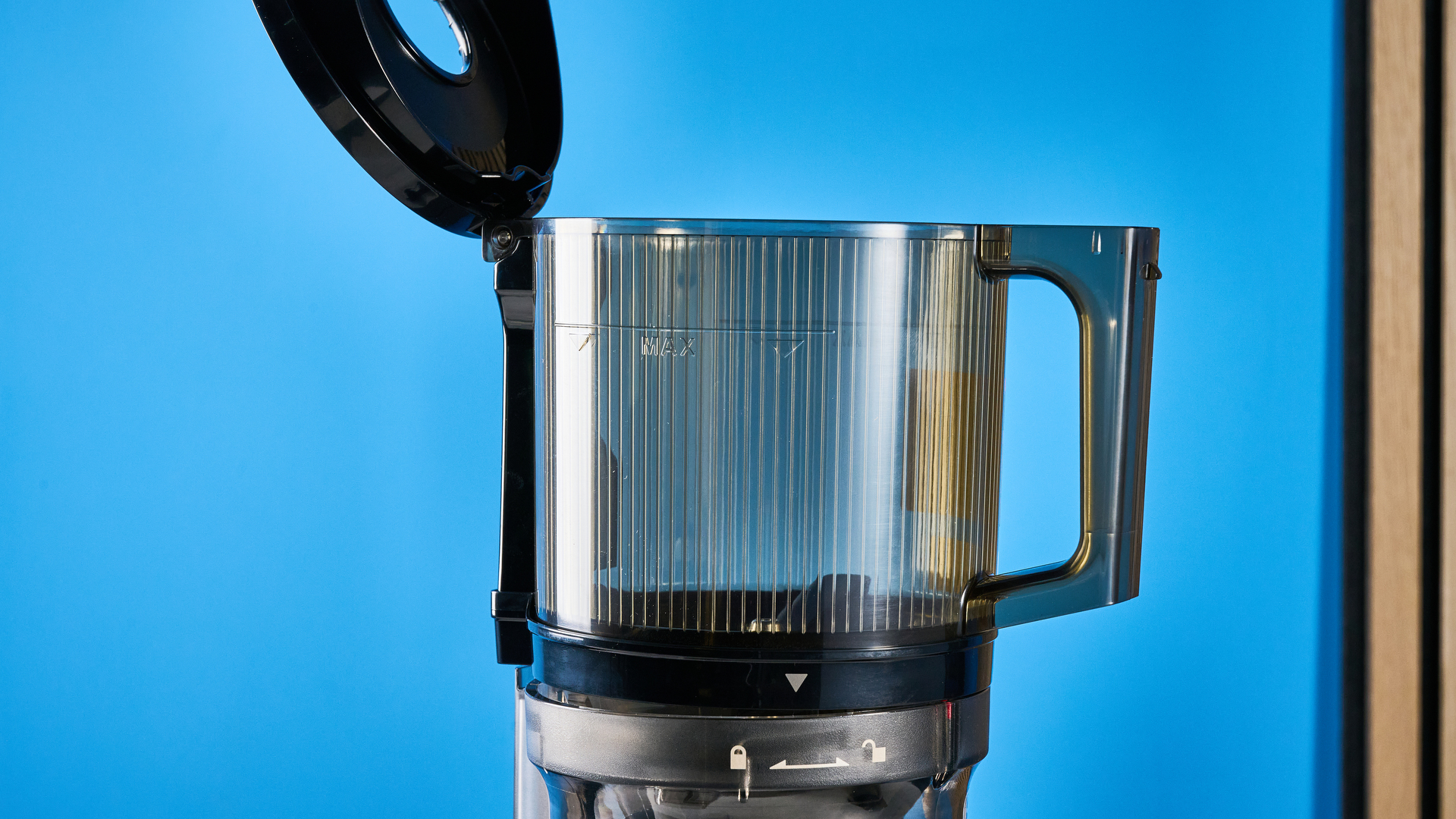 Kuvings Auto8 hands-free slow juicer photographed on a blue background.