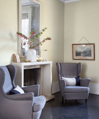room with grey sofa white flower vase and cream coloured wall