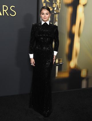 A photo of Selena Gomez at the 2024 Governors Awards wearing a beaded Ralph Lauren dress with a pointed white collar and folded cuffs.