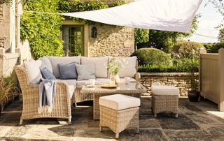 patio with white shade sail over rattan sofa patio set