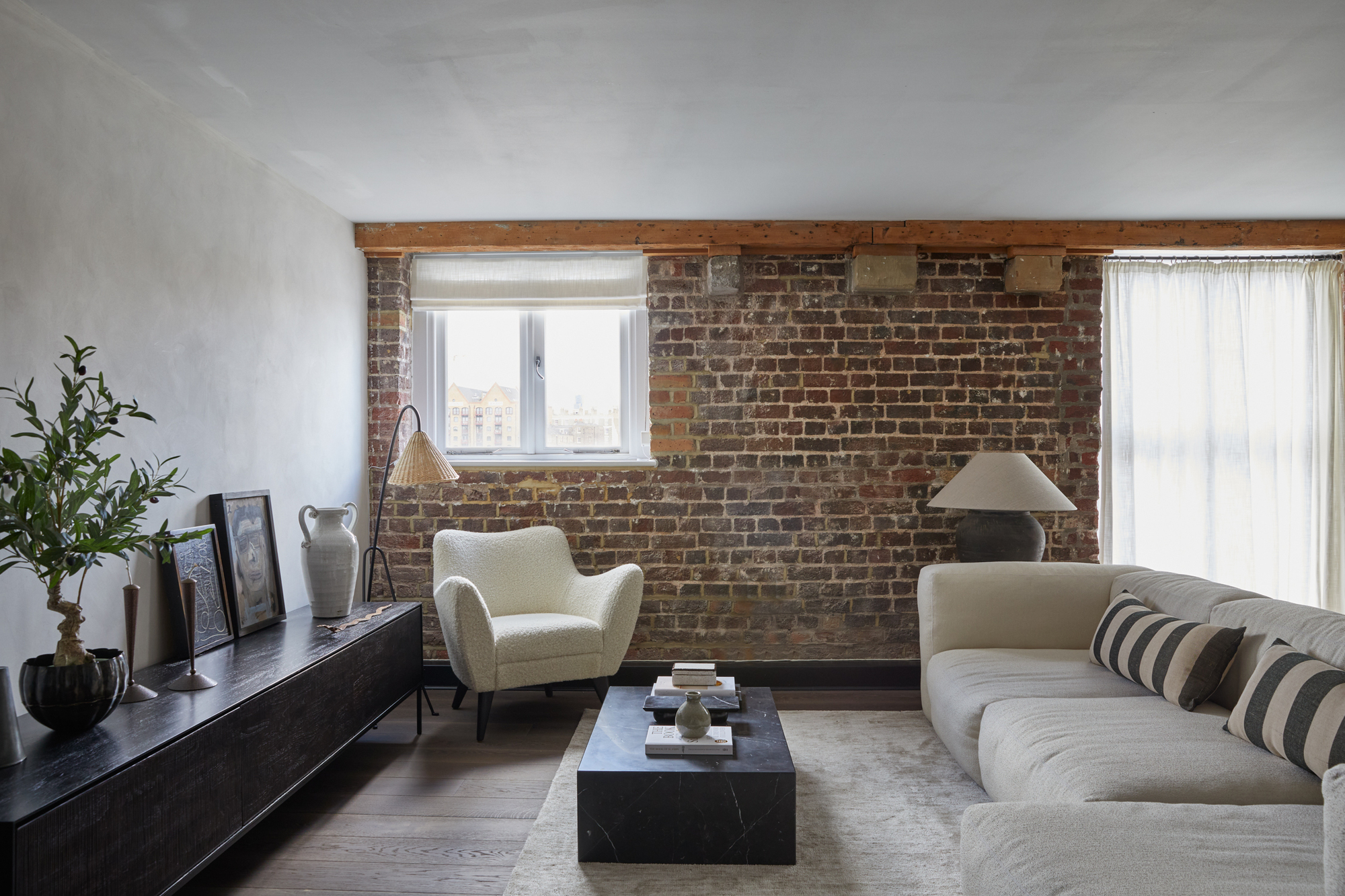 An industrial style London home with a low profile sofa and exposed brick wall by Annie Harrison, Fare Inc, interior design