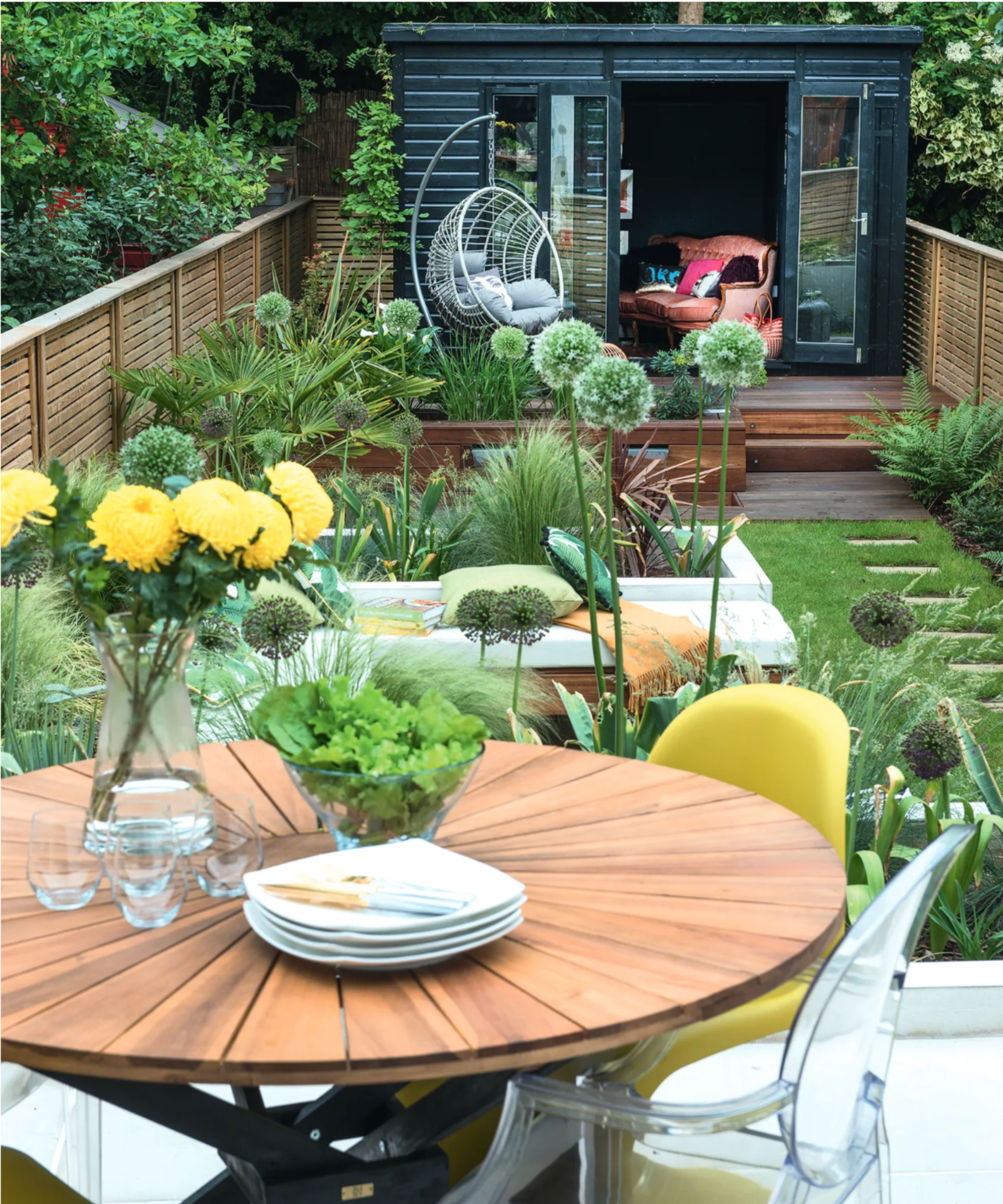 small garden design with shed, lawn, stepping stones, garden table and chairs and egg chair