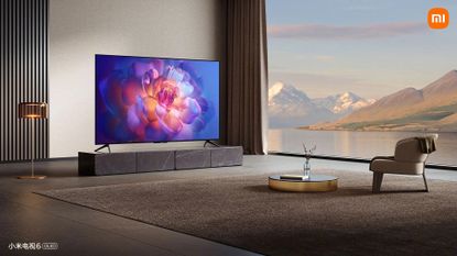 Xiaomi Mi TV 6 OLED in house, sitting on bench with large windows nearby showing a landscape view