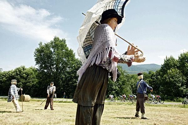 The peloton rushes by the typical straw figures in the Pyrenees.