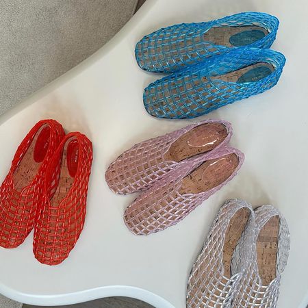 Photo of the Row jelly ballet flats on white table in red, pink, white, and blue.