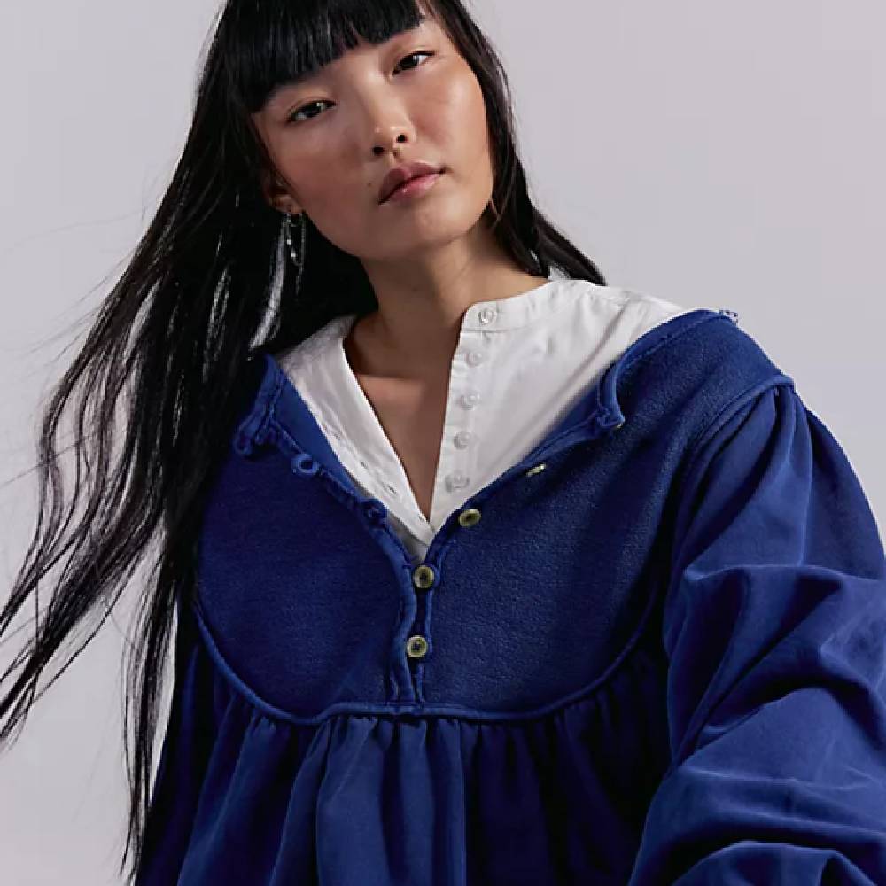 A female model wearing a dark blue fleece and a white blouse from Free People.