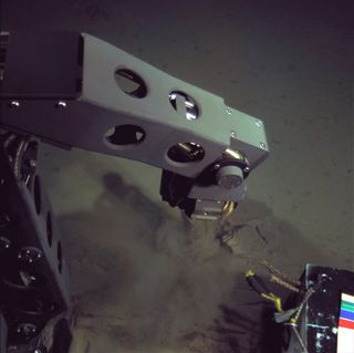 A specialized manipulator arm of the newly built hybrid remotely operated vehicle Nereus samples sediment from the deepest part of the world's ocean—the Mariana Trench.