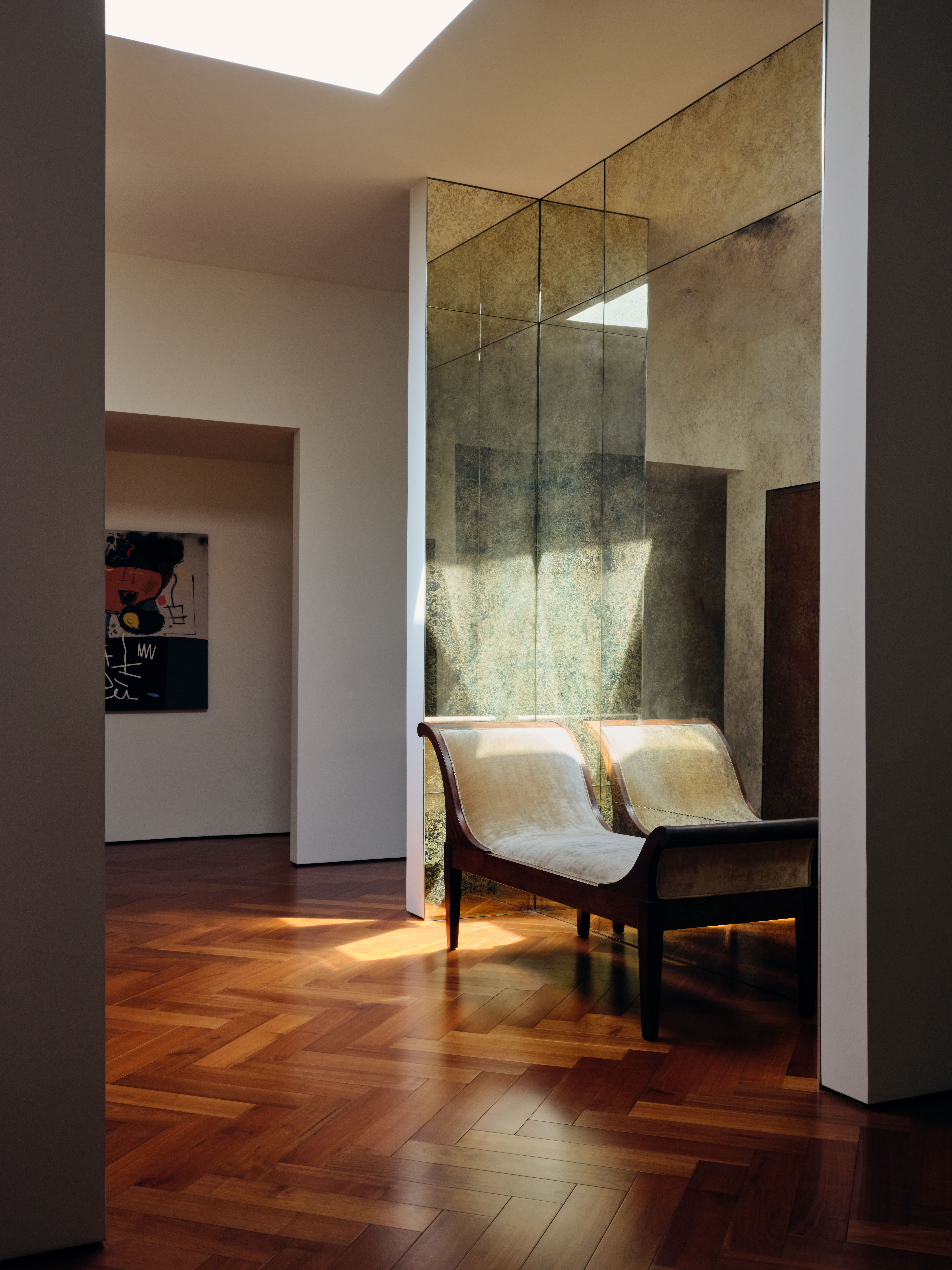Light pours in from the ceiling onto a vintage daybed in the hallway