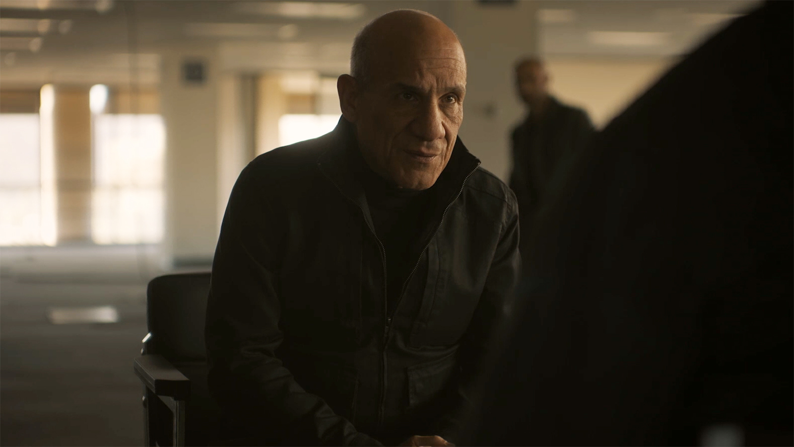 A bald man sitting in a chair opposite Aaron Pierre's John Stewart in Lanterns episode 2