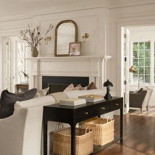 A black console table in a living room with two wicker baskets on the bottom shelf