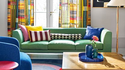 green sofa in living room with patterned curtains