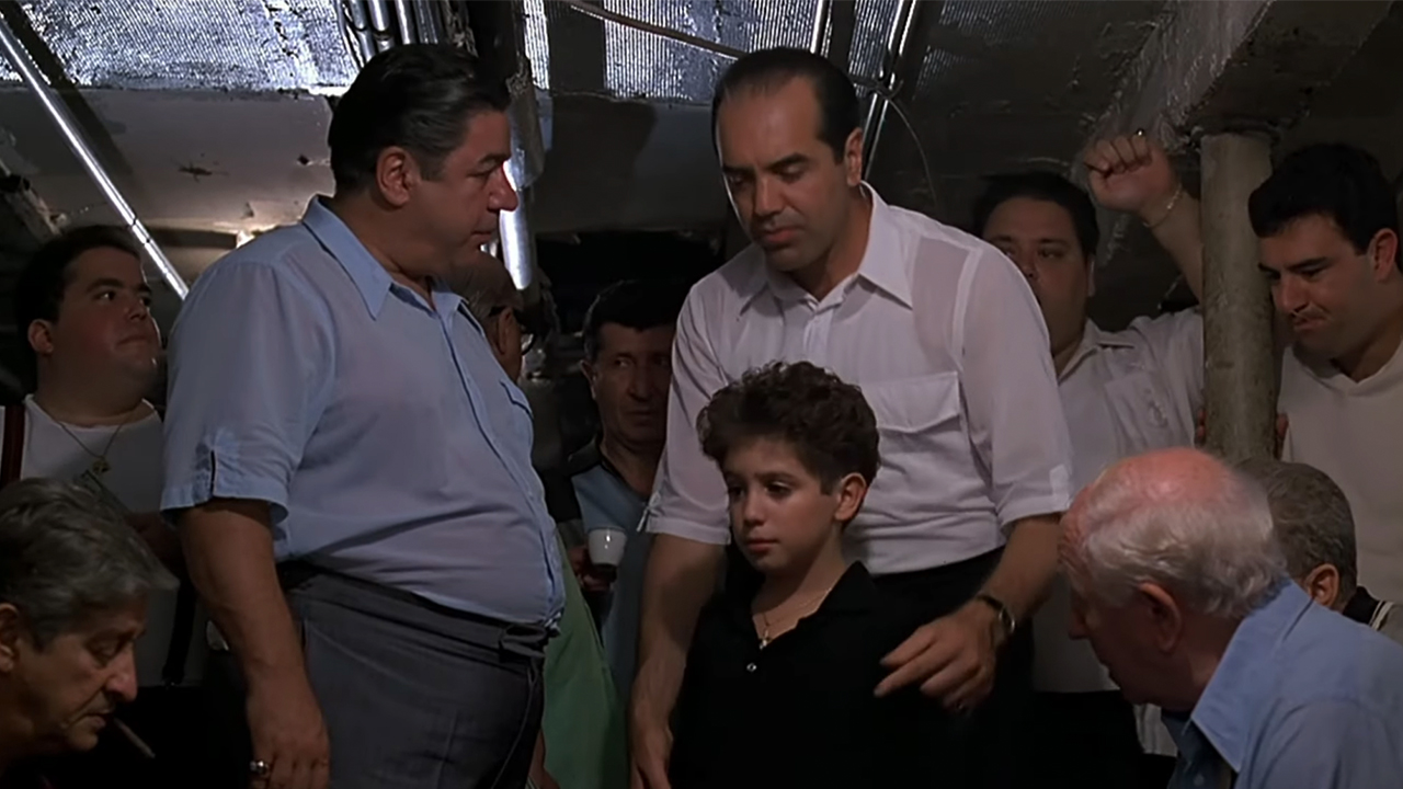 Chazz Palminteri with his hands on the shoulder of a boy, teaching him how to play craps