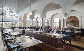 Alternative view of the main room at Origin Grill & Bar, Singapore featuring wood flooring, pendant lights, reddish brown and blue wooden seating, wooden tables with tableware and a view of the trees outside through the windows. The room design features multiple arches