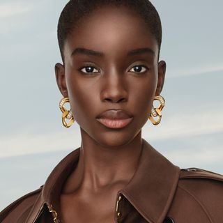 a close up of a model wearing a brown trench coat and Burberry beauty