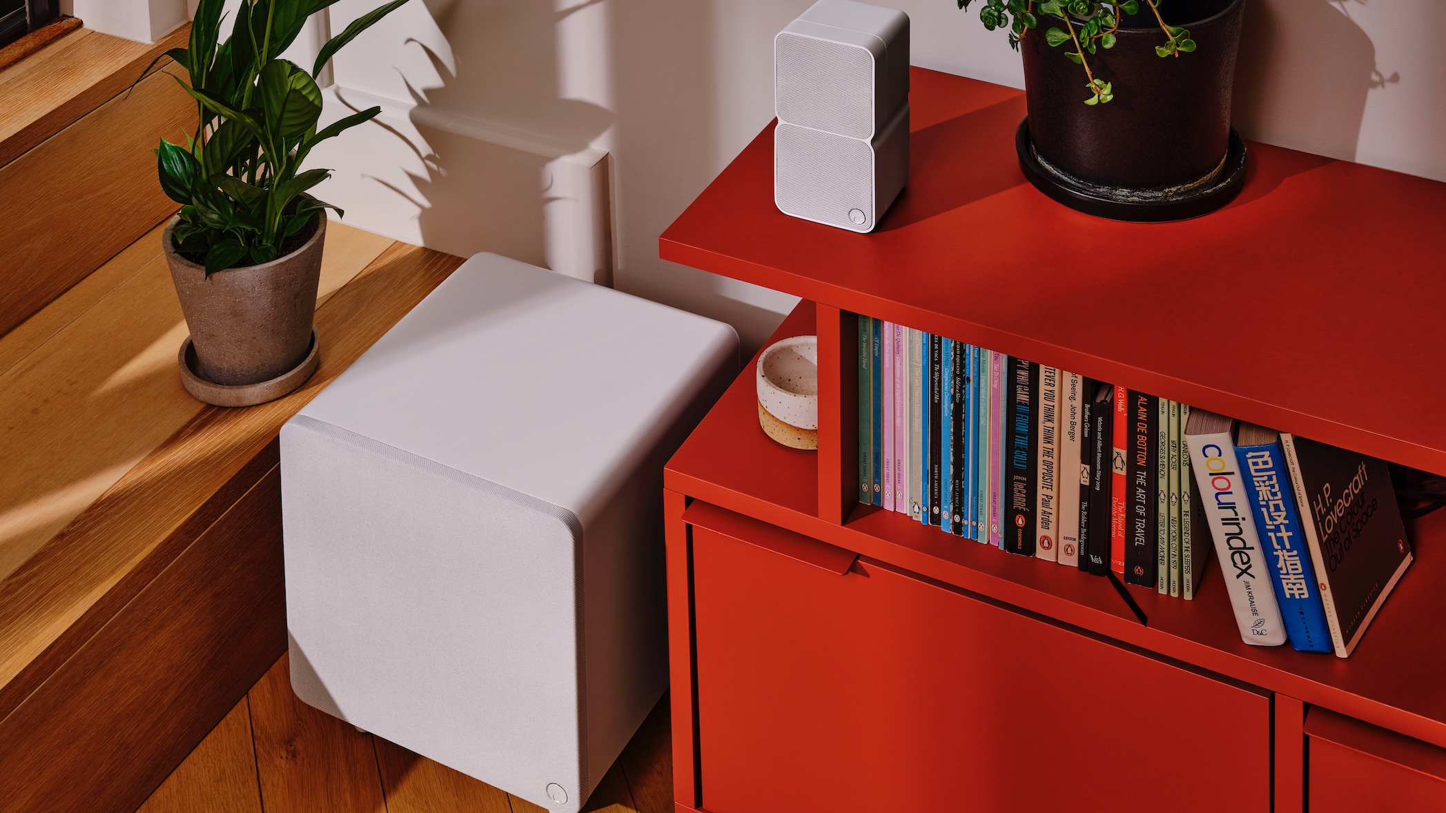 A Cambridge Audio MSX subwoofer and two mini modular speakers positioned on a red media unit in a living area.