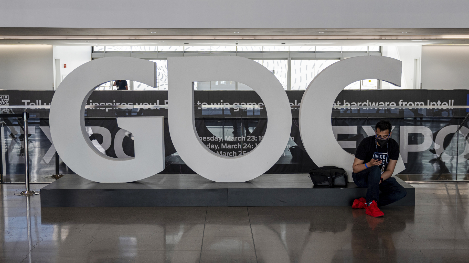 An attendee sits next to a "GDC" sign inside an exhibition hall during the Game Developers Conference at the Moscone Center in San Francisco, California, U.S., on Tuesday, March 22, 2022. The weeklong video game industry conference is San Francisco's biggest convention since public health orders upended the events business two years ago, reported the San Francisco Chronicle.
