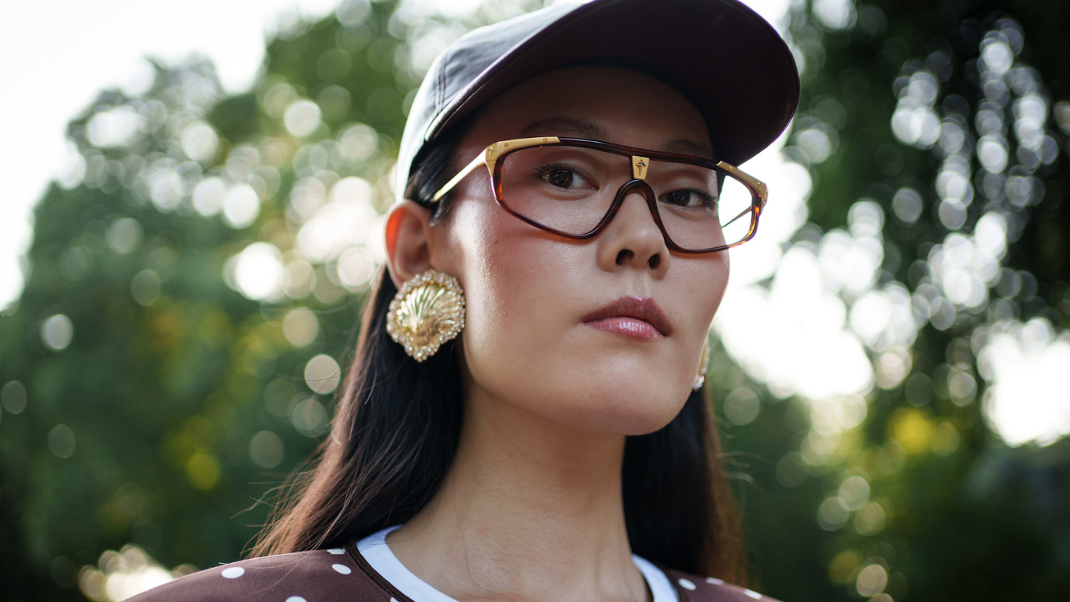 woman with a baseball hat, sunglasses and brown blush