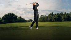 A golfer teeing off with Scheels golf gear