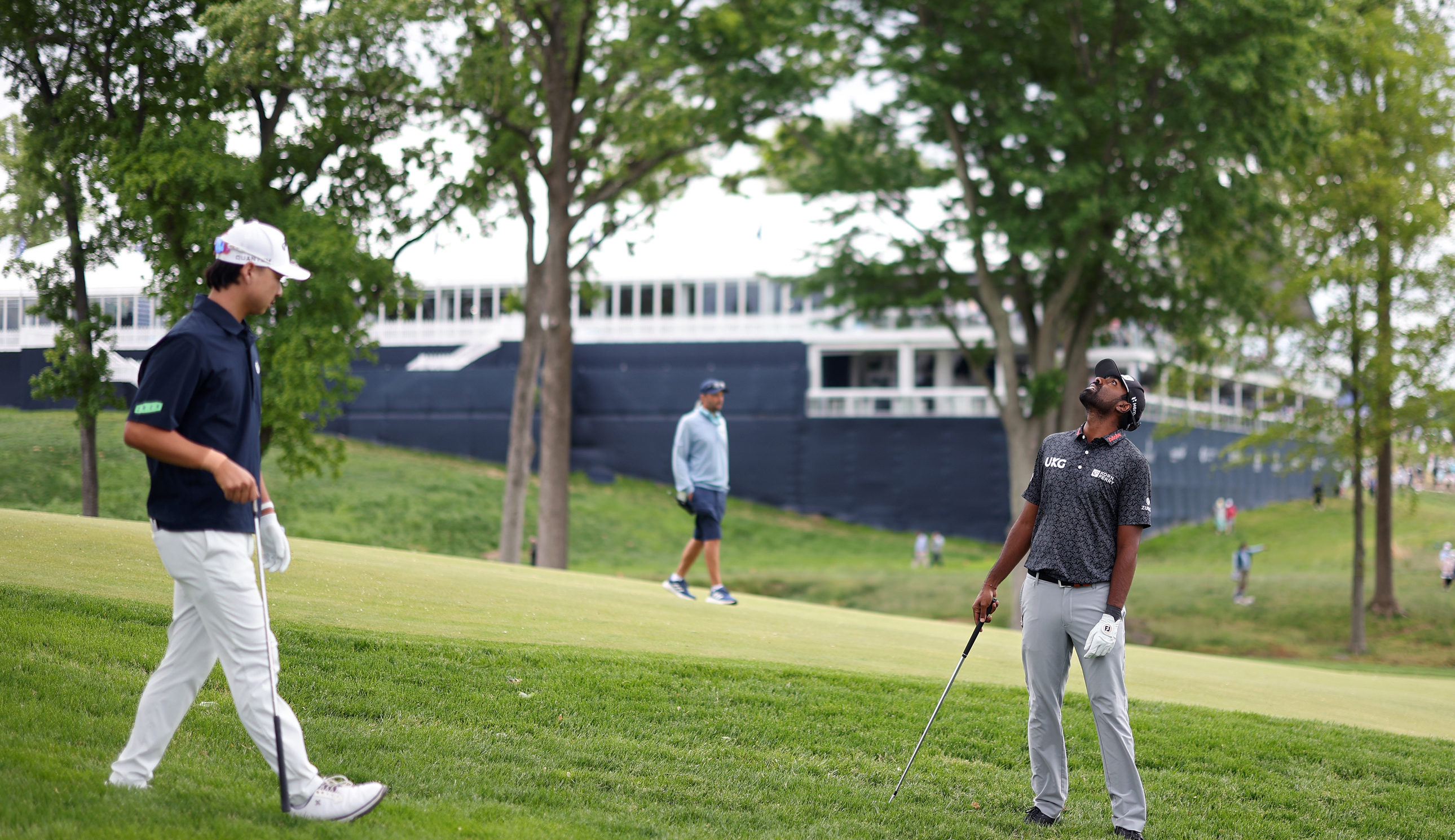 Min Woo Lee and Sahith Theegala search for a golf ball