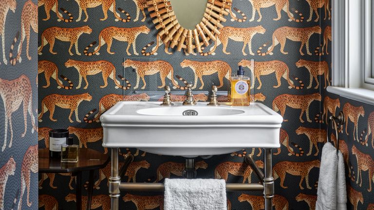 An example of cloakroom ideas showing a cloakroom with a white sink in front of leopard patterned wallpaper