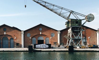 Daytime image of the Historical Museum of Bosnia and Herzegovina in Venice, water front, red brick building, crane, blue sky