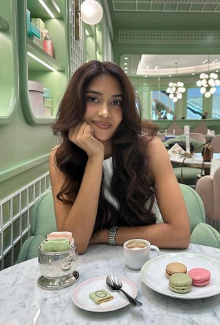 Mishti Rahman with chocolate-colored curls in a Ladurée cafe