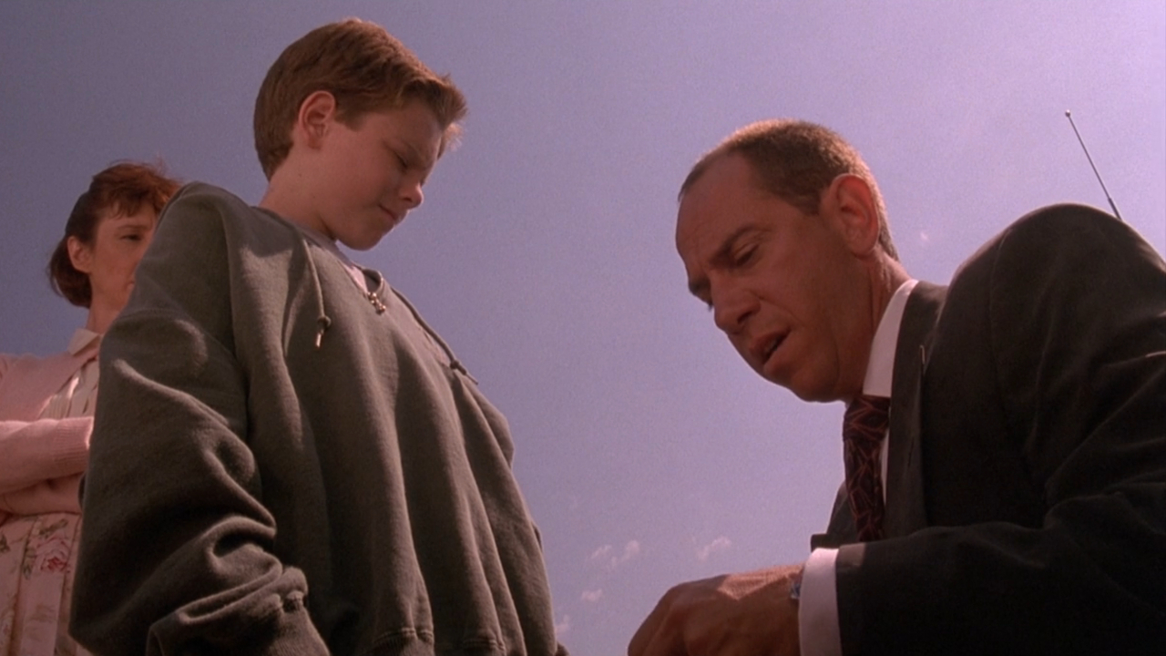 Brian Bonsall and Miguel Ferrer talking in a parking lot in Blank Check.