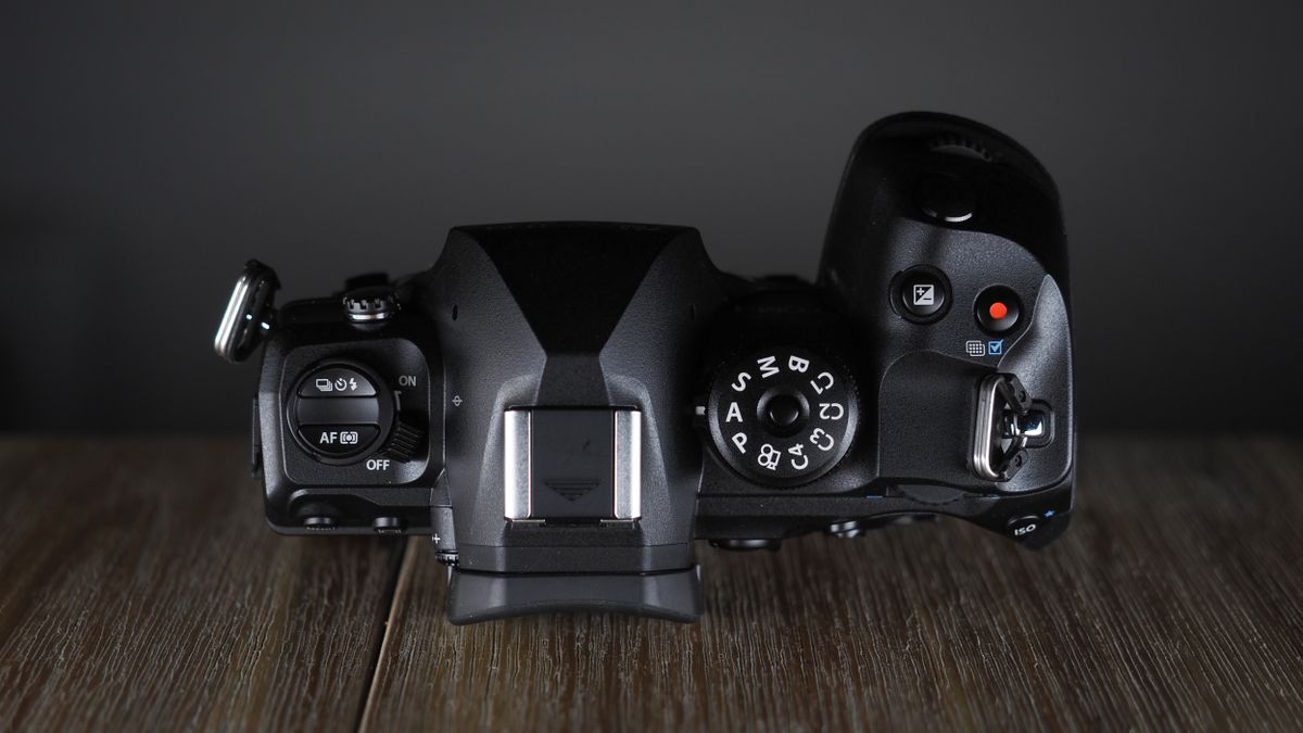 OM System OM-1 Mark II on a wooden surface, against a dark background