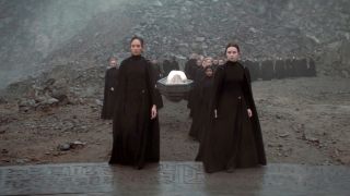 A procession of Bene Gesserit leading a coffin down a path in Dune: Prophecy