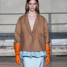 Photo of model wearing khaki, baby blue, and orange spring color combination on runway.